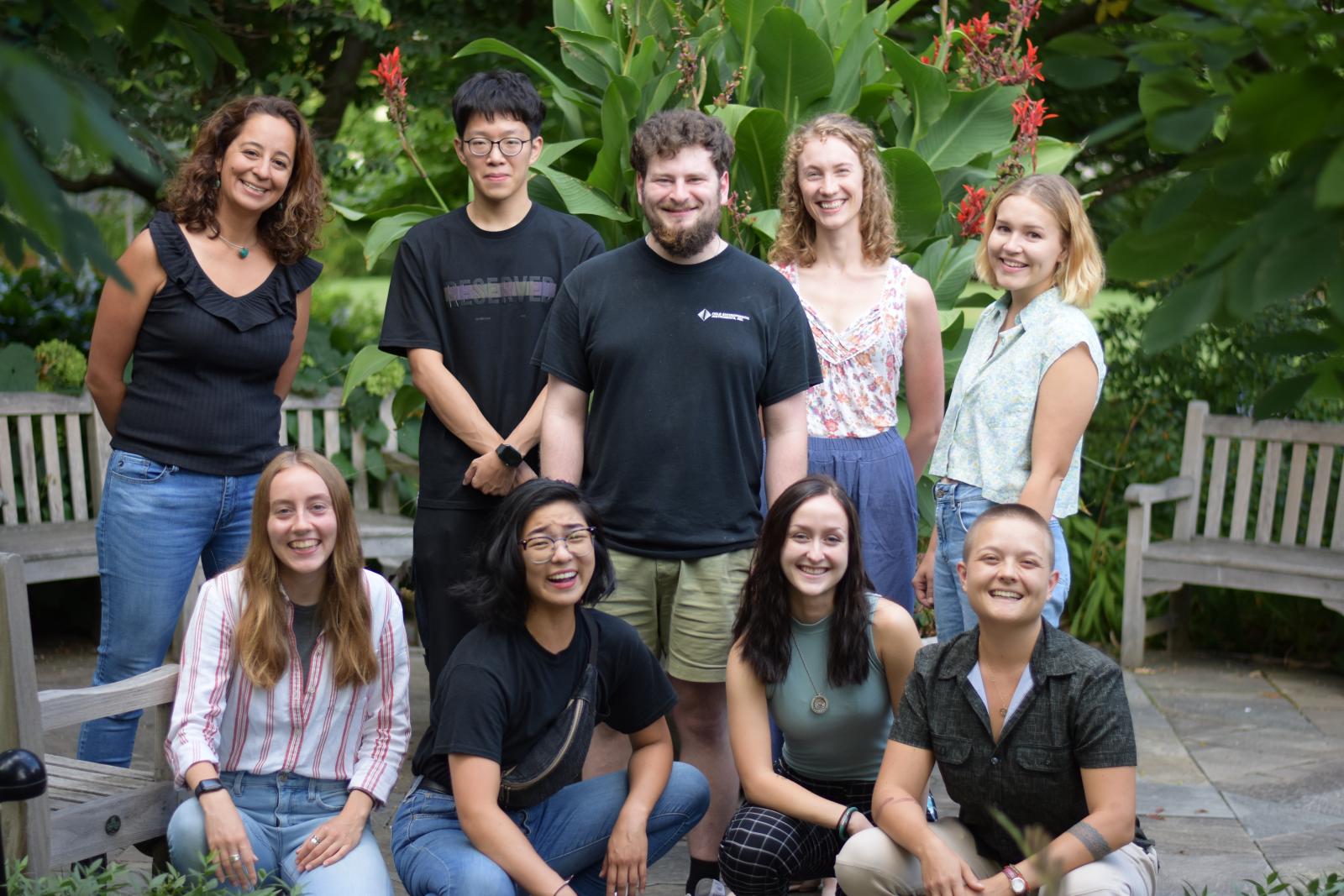 Graduate students pose in two rows in a garden