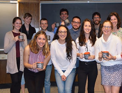 A group of student presenters holding coffee mugs